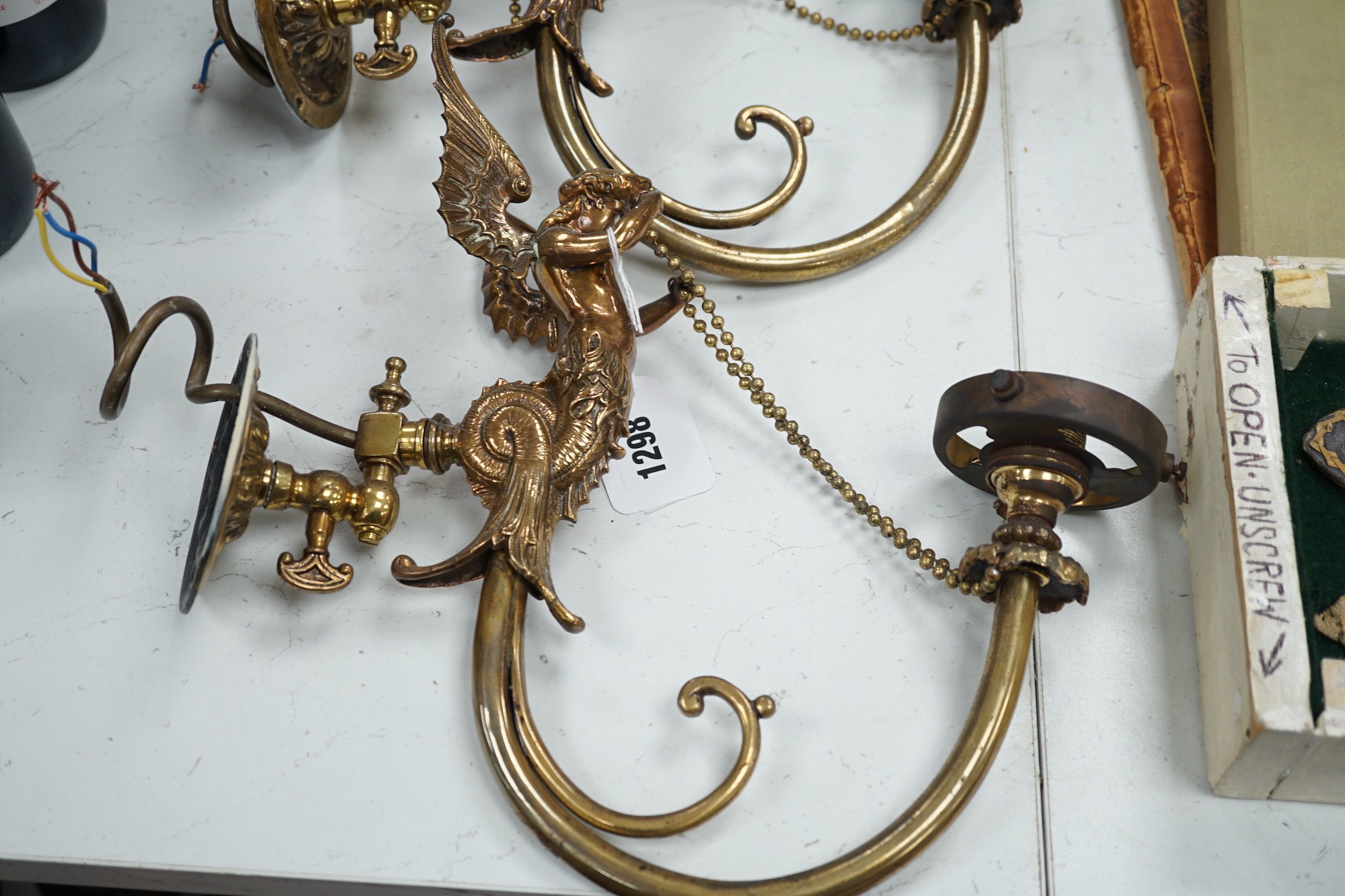 A pair of brass winged caryatid wall lights with green shades, 30cms deep